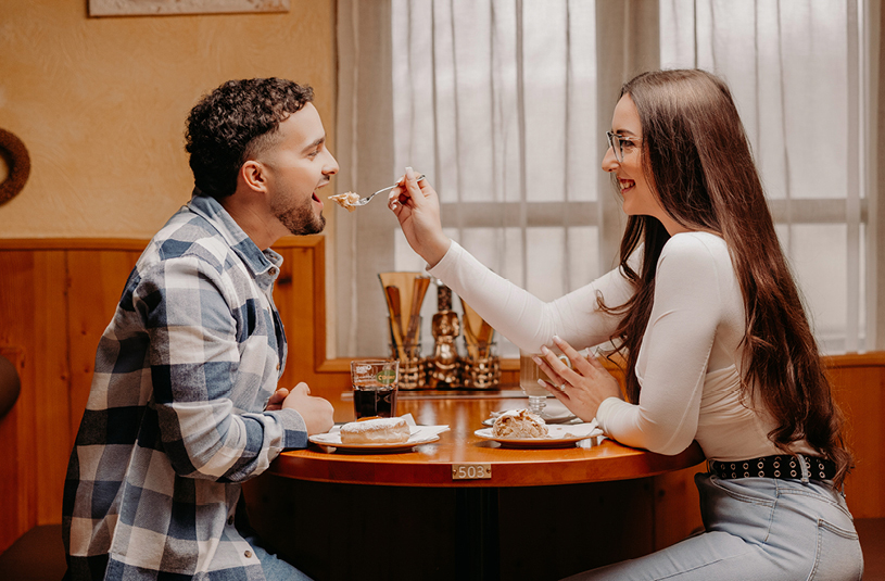 Ein Paar beim gemeinsamen Essen, ein Mann wird dabei von einer Frau gefüttert.