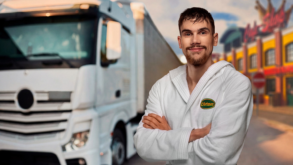 Ein frisch geduschter Trucker im Vordergrund vor seinem LKW.