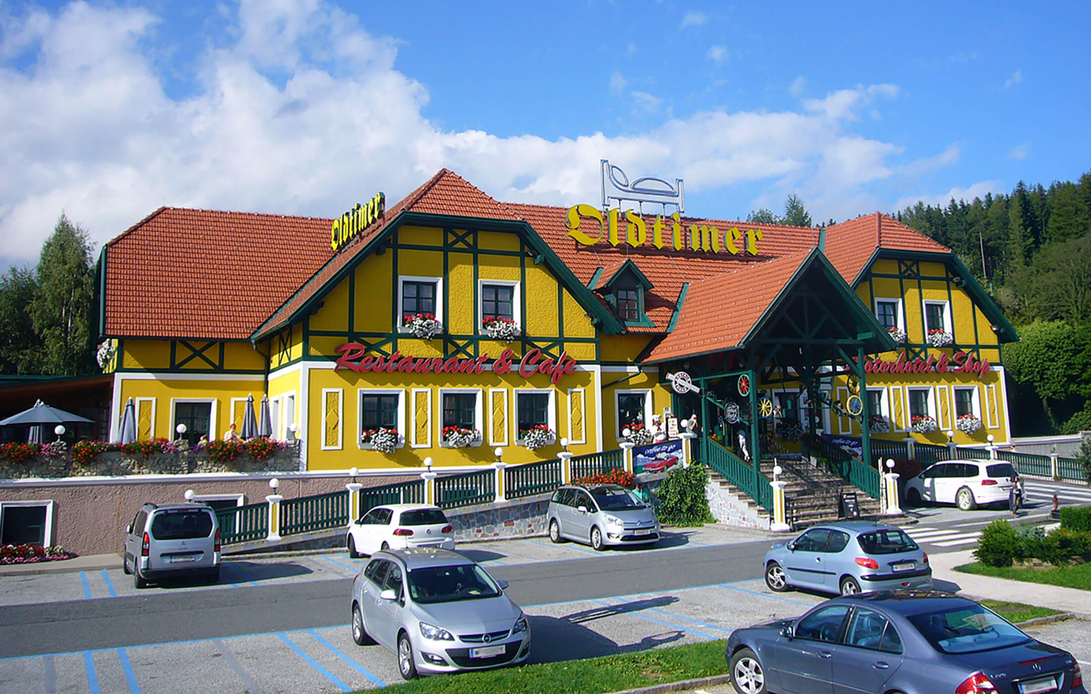 Blick auf die Oldtimer Raststation auf der Pack mit parkenden Autos im Vordergrund.