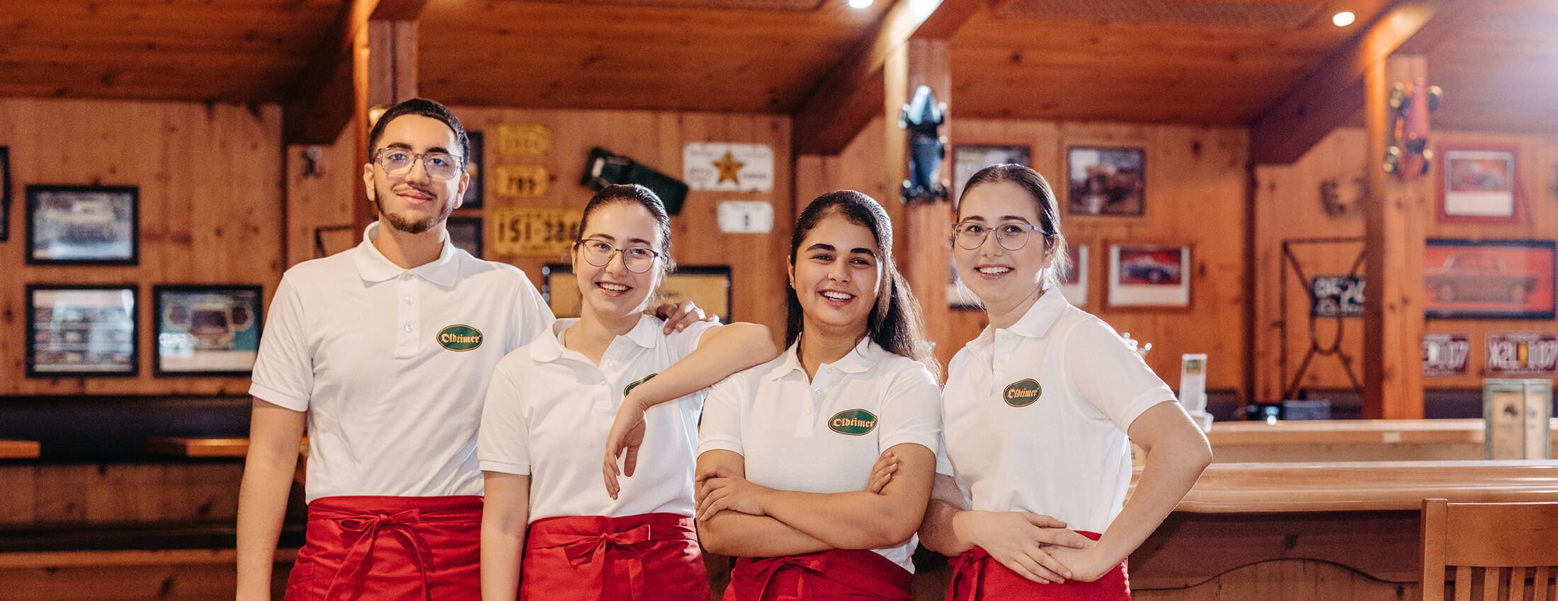 Bild von vier, fröhlichen Mitarbeitern der Oldtimer Raststationen in einer holzgetäfelten Gaststube.