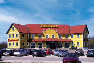 Blick auf den Oldtimer Standort Guntramsdorf mit parkenden Autos im Vordergrund.