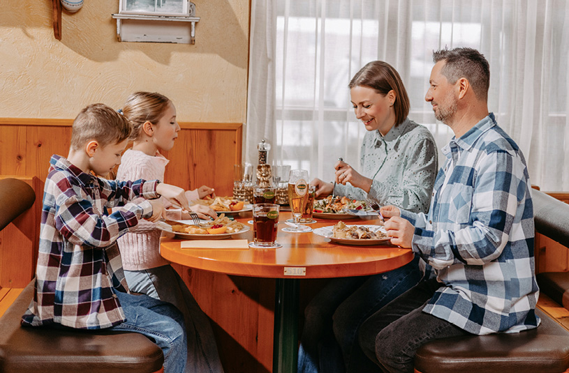 Eine Familie beim gemütlichen, gemeinsamen Essen in einer Gaststube.