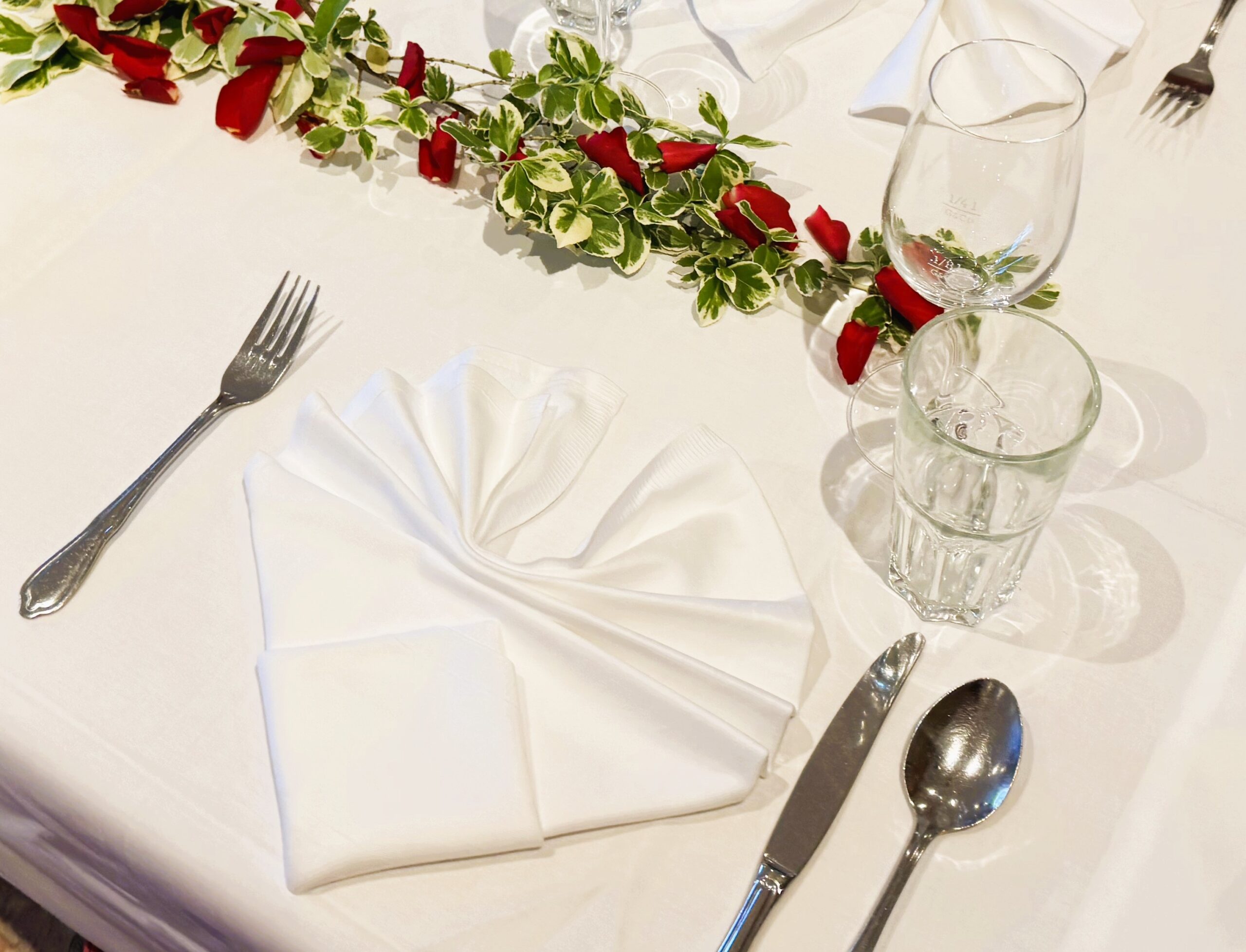 Besteck, Serviette, Gläser und Dekoration befinden sich auf einem Tisch.